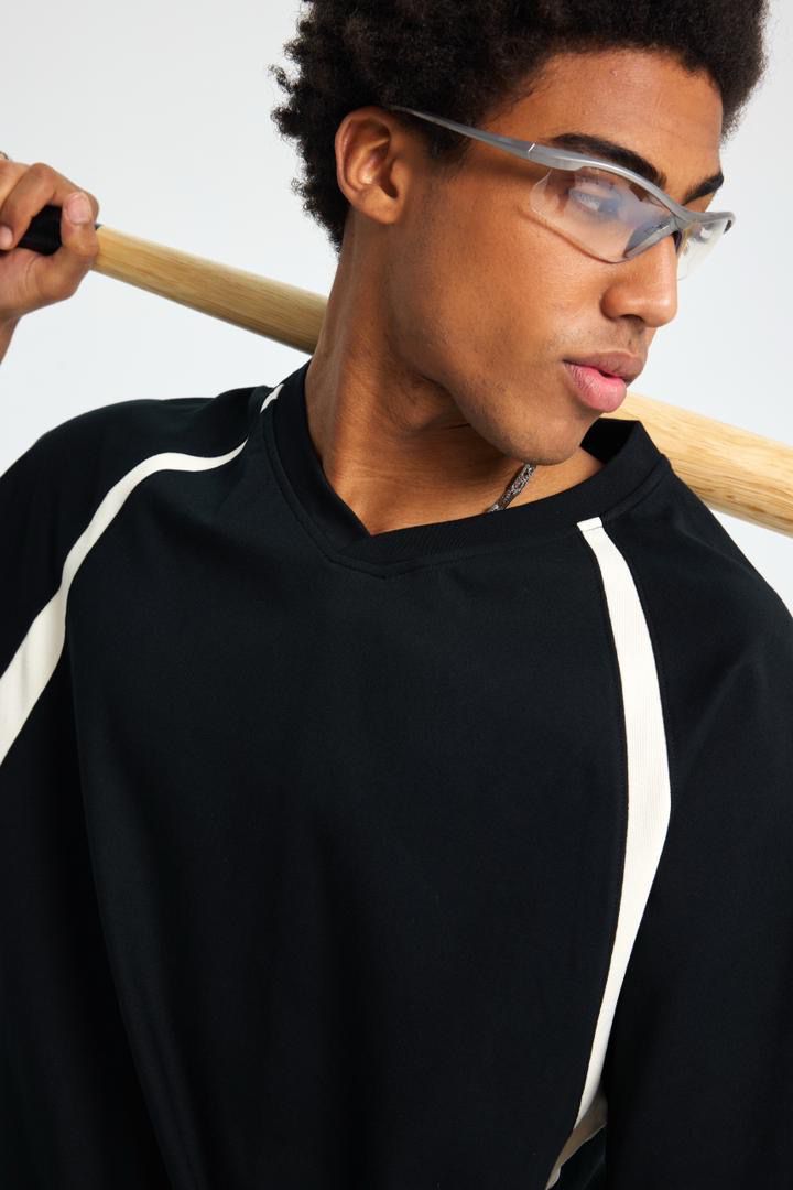 Person wearing glasses and a black outfit with white stripes, holding a wooden object.