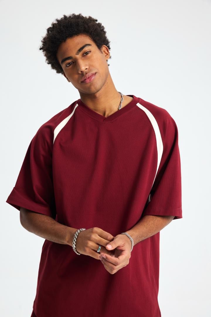 Man wearing a maroon sports jersey with white accents on a white background