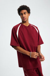 Person wearing a maroon scrub set with white accents on a plain background