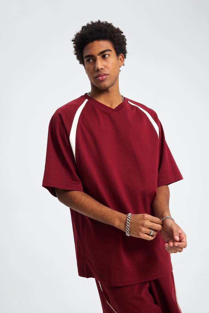 Person wearing a maroon scrub set with white accents on a plain background